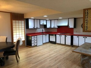 A compact kitchen with white cabinets, a red countertop, and a dining area with a round table and chairs. - Unique Home Peaceful Near Boulder Dogs Ok (Longmont)