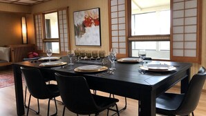 A dining area with a black table set for four, surrounded by black chairs, with a traditional Japanese sliding door and a painting on the wall.