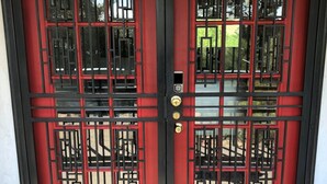 A red and black double door with a traditional design, featuring a keyhole and a lock.