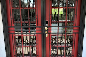 Une porte à deux battants, rouge et noire, au design traditionnel, dotée d’un trou de serrure et d’une serrure.