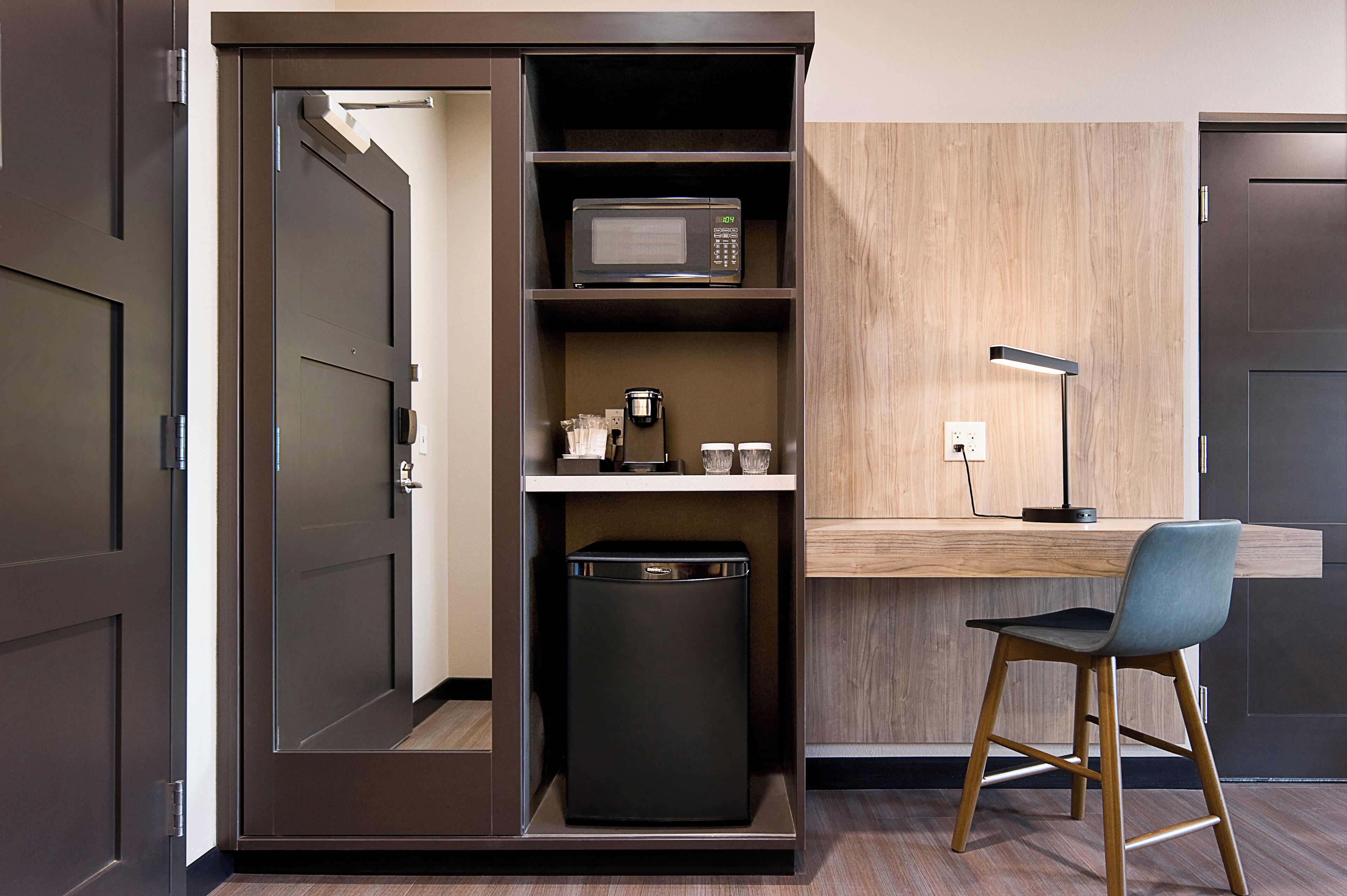 A compact kitchenette with a microwave, coffee maker, and a small trash bin.