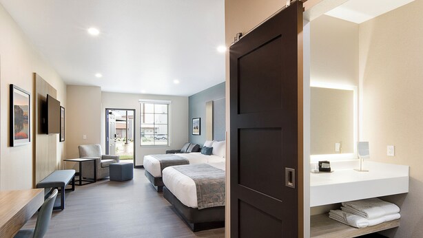 A modern hotel room with a large bed, a desk, a chair, and a small seating area. - ClubHouse Hotel & Suites - Rapid City (Rapid City)