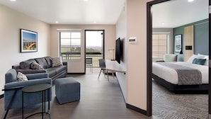 A modern hotel room with a balcony, a sofa, a desk, and a bed. - ClubHouse Hotel & Suites - Rapid City (Rapid City)