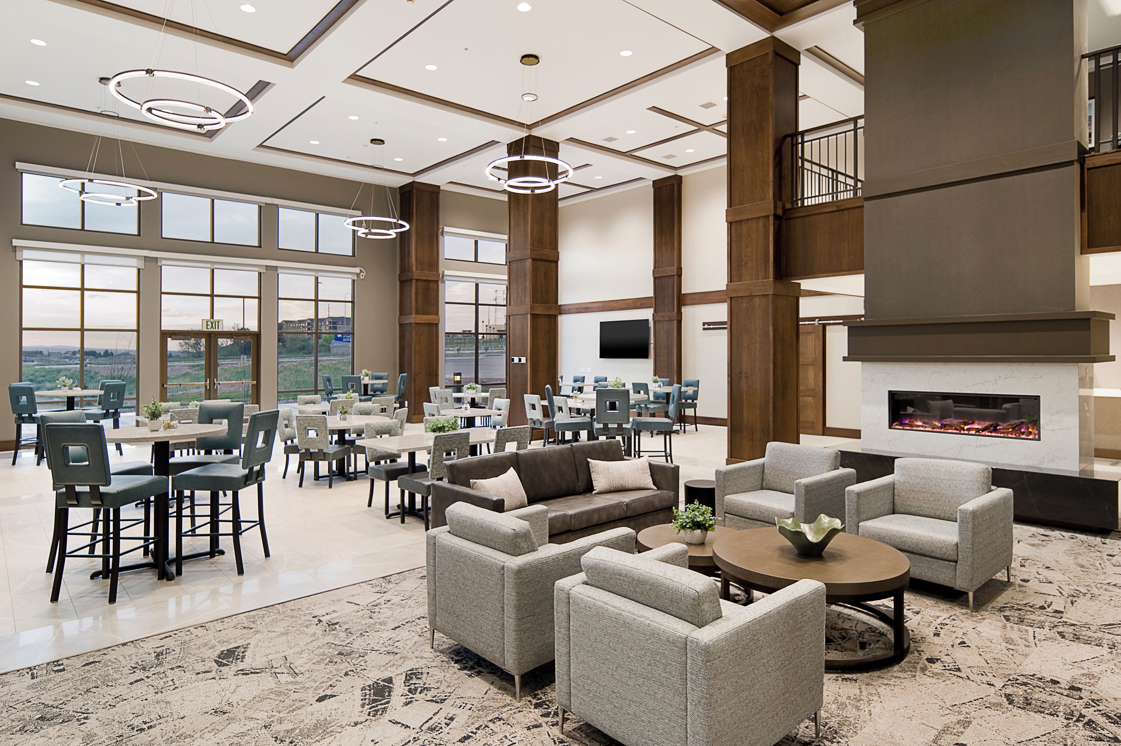 A spacious indoor area with multiple seating arrangements, large windows, and a fireplace.