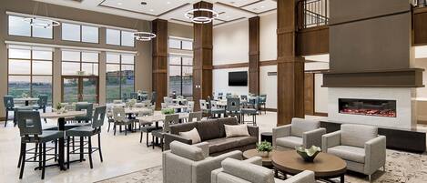 A spacious indoor area with multiple seating arrangements, large windows, and a fireplace.