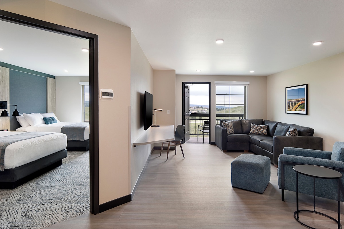 Une chambre d’hôtel moderne dotée d’un grand lit, d’un bureau, d’un canapé et d’un balcon avec vue.