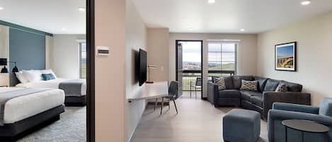 Una habitación de hotel moderna con una cama grande, un escritorio, un sofá y un balcón con vistas.