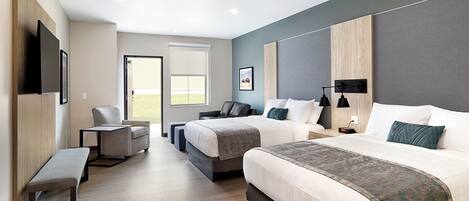 A hotel room with two beds, a bench, a chair, a desk, and a window.