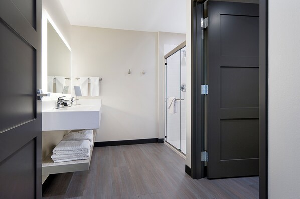 Un baño moderno con lavamanos blanco, toallero y puerta de ducha de vidrio.