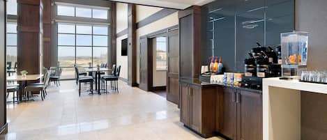 A modern kitchen with a bar area, large windows, and a dining area with chairs and tables.