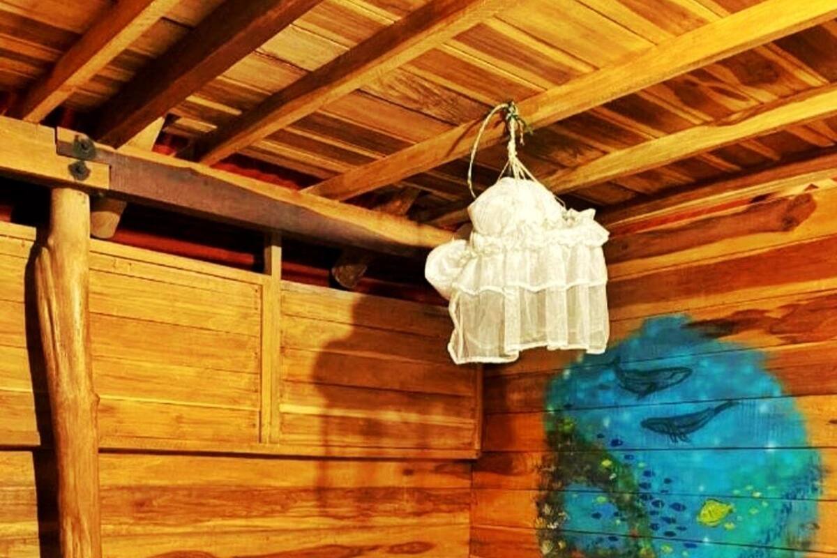 A wooden cabin room with a bed, a hanging light fixture, and a painted wall.