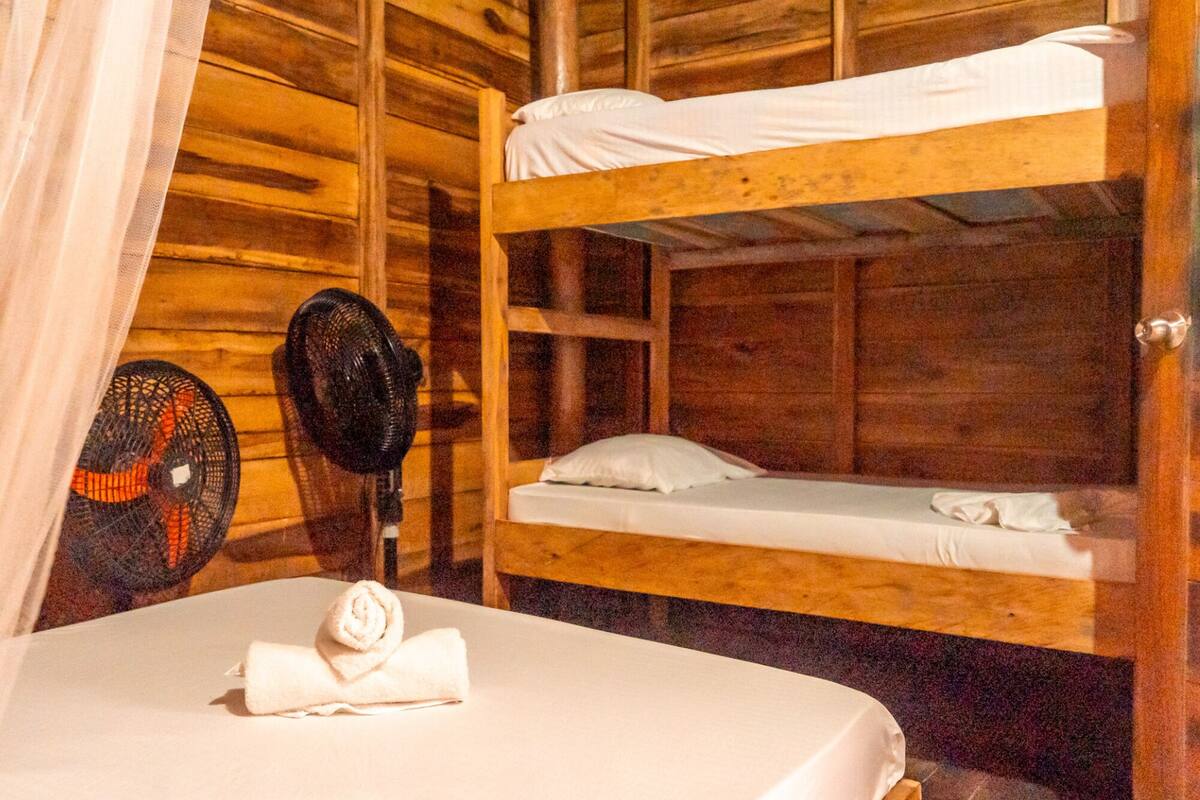 A bunk bed room with a bed, a fan, and a towel.