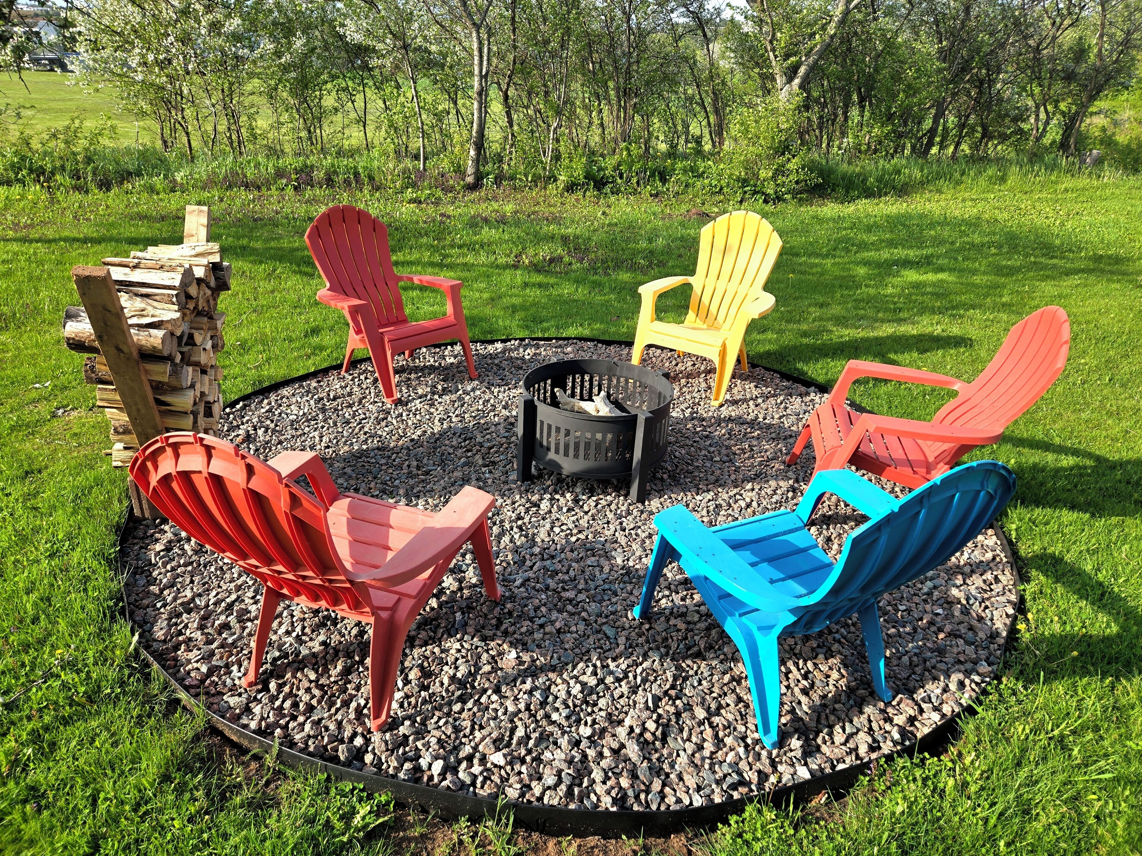 A circular seating area with Adirondack chairs in red, yellow, blue, and orange colors, centered around a fire pit.
