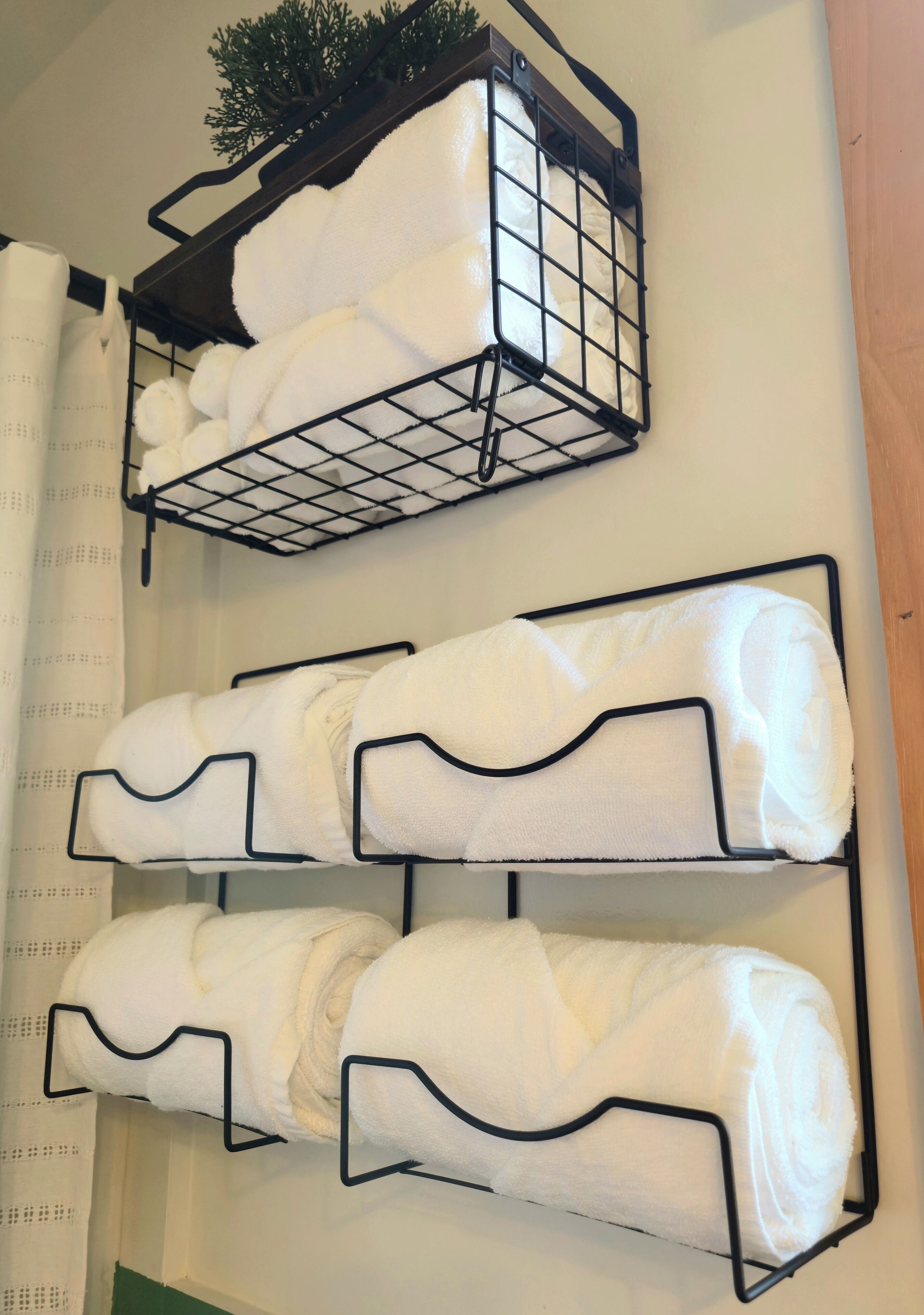 Toallero de pared con tres estantes que sostienen toallas enrolladas.