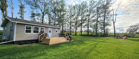 A single-story house with a front porch, a small deck, and a grassy yard.