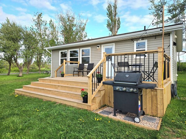Une maison dotée d’un patio couvert, d’un barbecue et de meubles pour se détendre à l’extérieur.