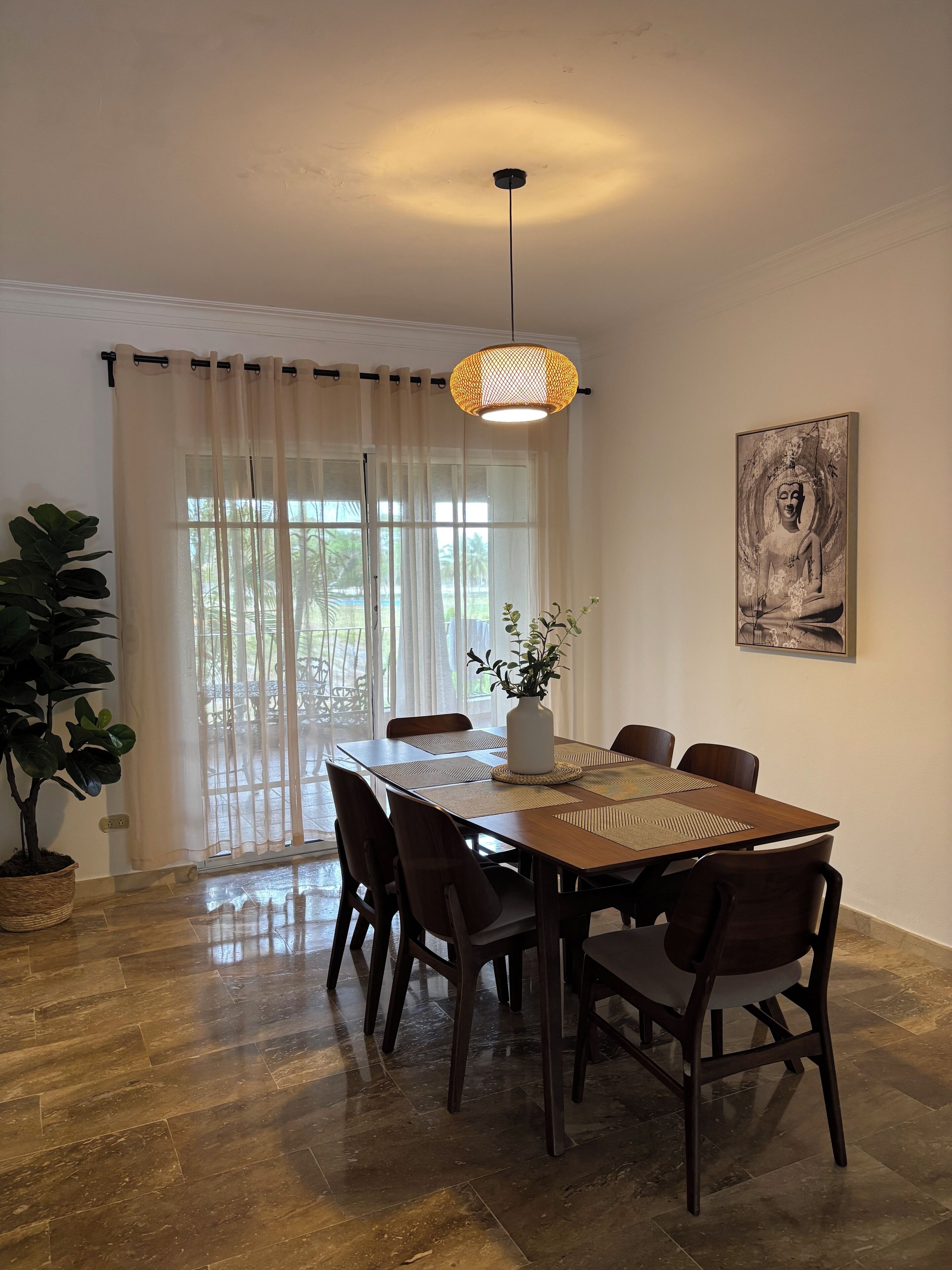 Un comedor con una mesa de madera, sillas, una lámpara colgante y un cuadro en la pared.