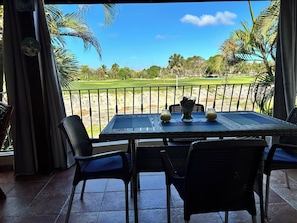 A table with chairs on a balcony overlooking a golf course.