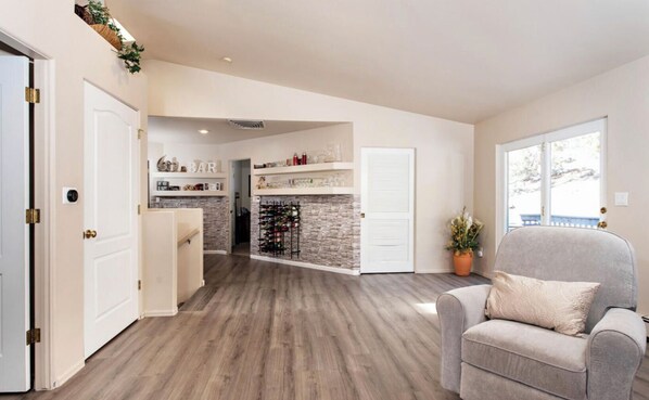 A spacious living area with a fireplace, a kitchen with a stone backsplash, and a view of the outdoors.