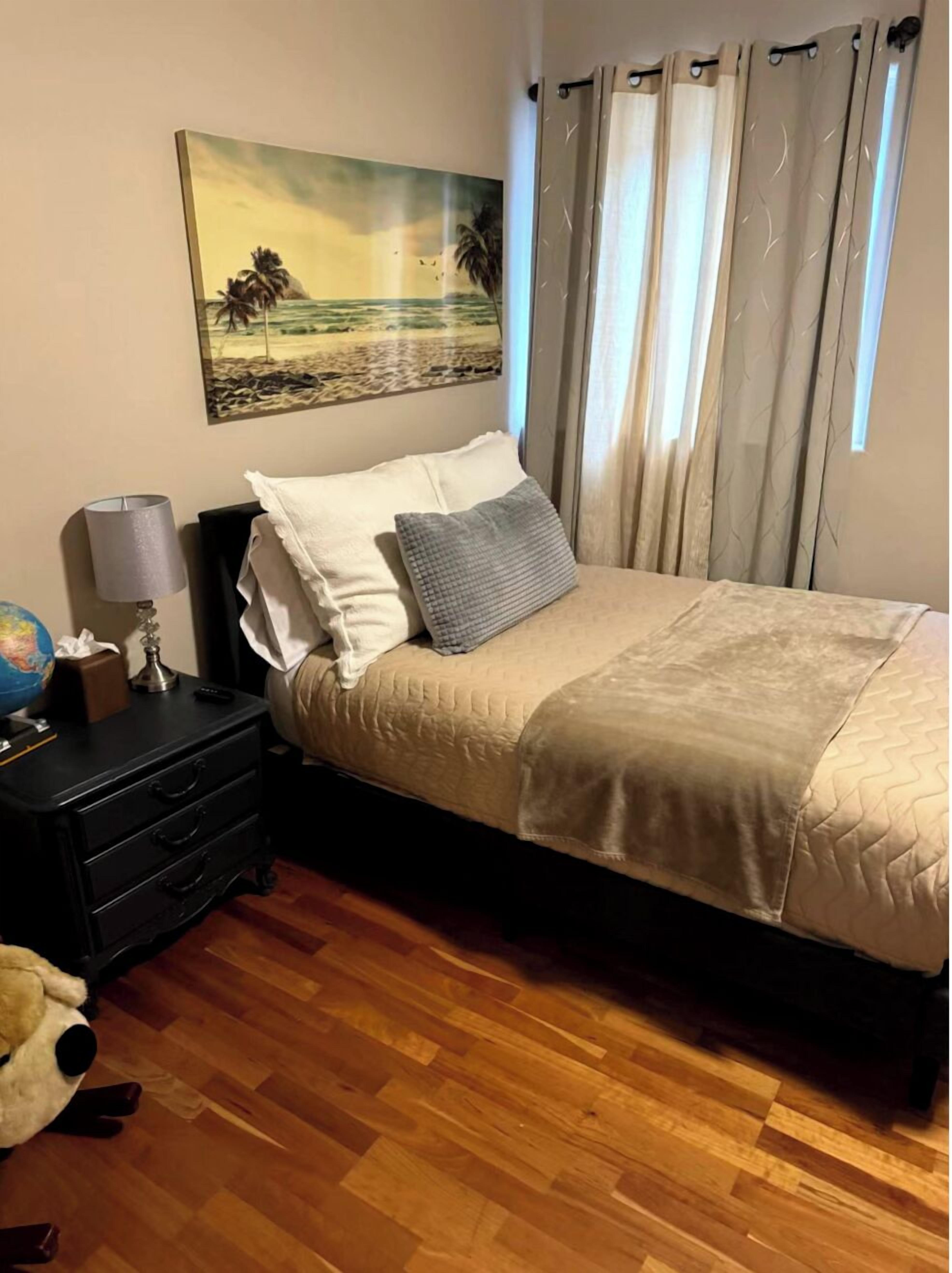 Ein ordentlich eingerichtetes Schlafzimmer mit Bett, Nachttisch, Lampe, Globus und Stofftier.