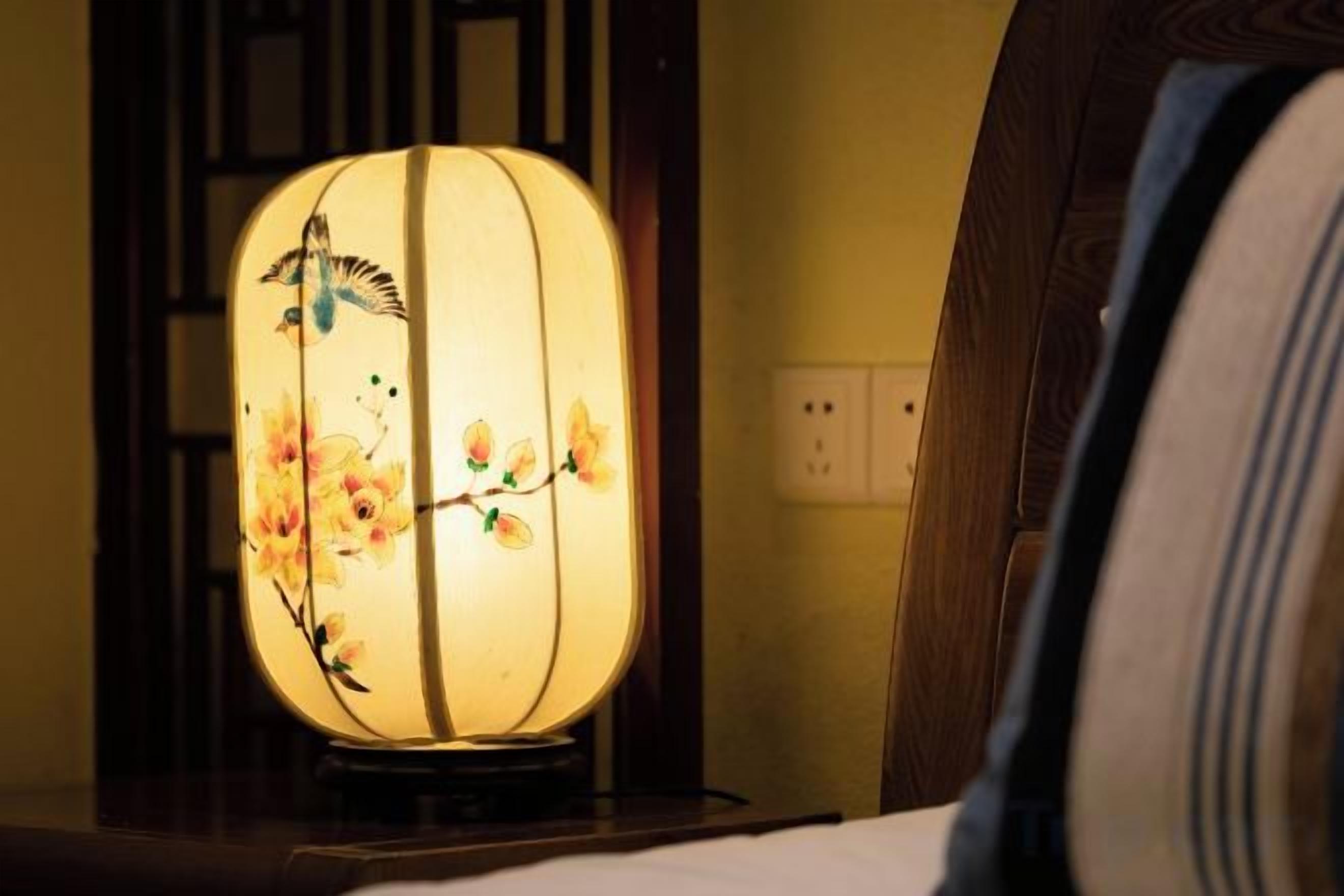 A traditional lamp with floral and bird designs on a stand.