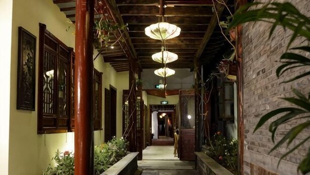 A corridor with wooden beams, hanging lanterns, and brick walls. - Zhouzhuang Hanshe Ziteng Bieyuan (Kunshan)