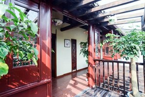 Un intérieur de style japonais traditionnel, avec un plancher en bois, un seuil en tatami et une vue sur un jardin par une porte en bois.