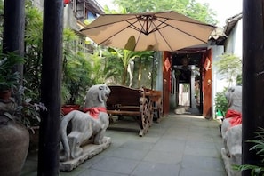 A courtyard with a wooden cart, stone lion statues, and an umbrella. - Zhouzhuang Hanshe Ziteng Bieyuan (Kunshan)