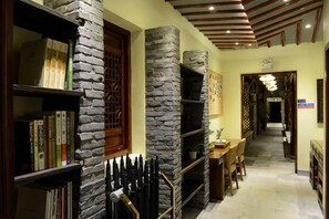 A hallway with stone pillars, bookshelves, a dining area, and a staircase. - Zhouzhuang Hanshe Ziteng Bieyuan (Kunshan)