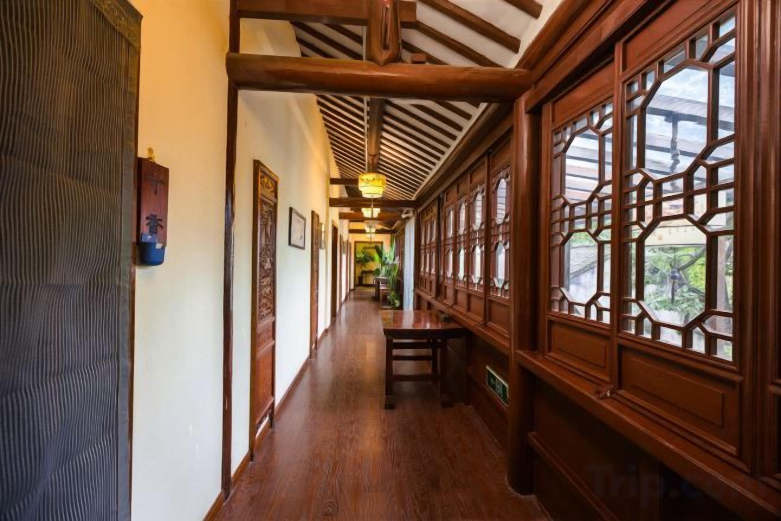 A corridor with wooden flooring, a bench, and traditional wooden windows.