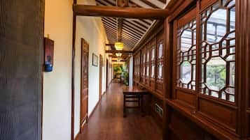 A corridor with wooden flooring, a bench, and traditional wooden windows.