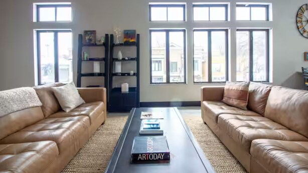 Un salon avec deux canapés en cuir, une table basse et une bibliothèque.