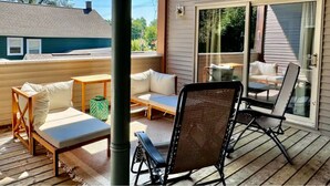Une terrasse extérieure couverte, aménagée avec un canapé, des fauteuils et une table.