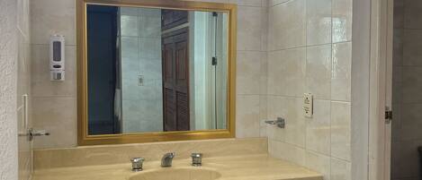A bathroom with a large mirror, two sinks, and a cabinet.