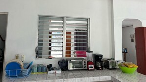 A kitchen with a window, a toaster, a blender, a coffee maker, and a bowl of bread. - TREEBU HOSTEL (Valladolid)