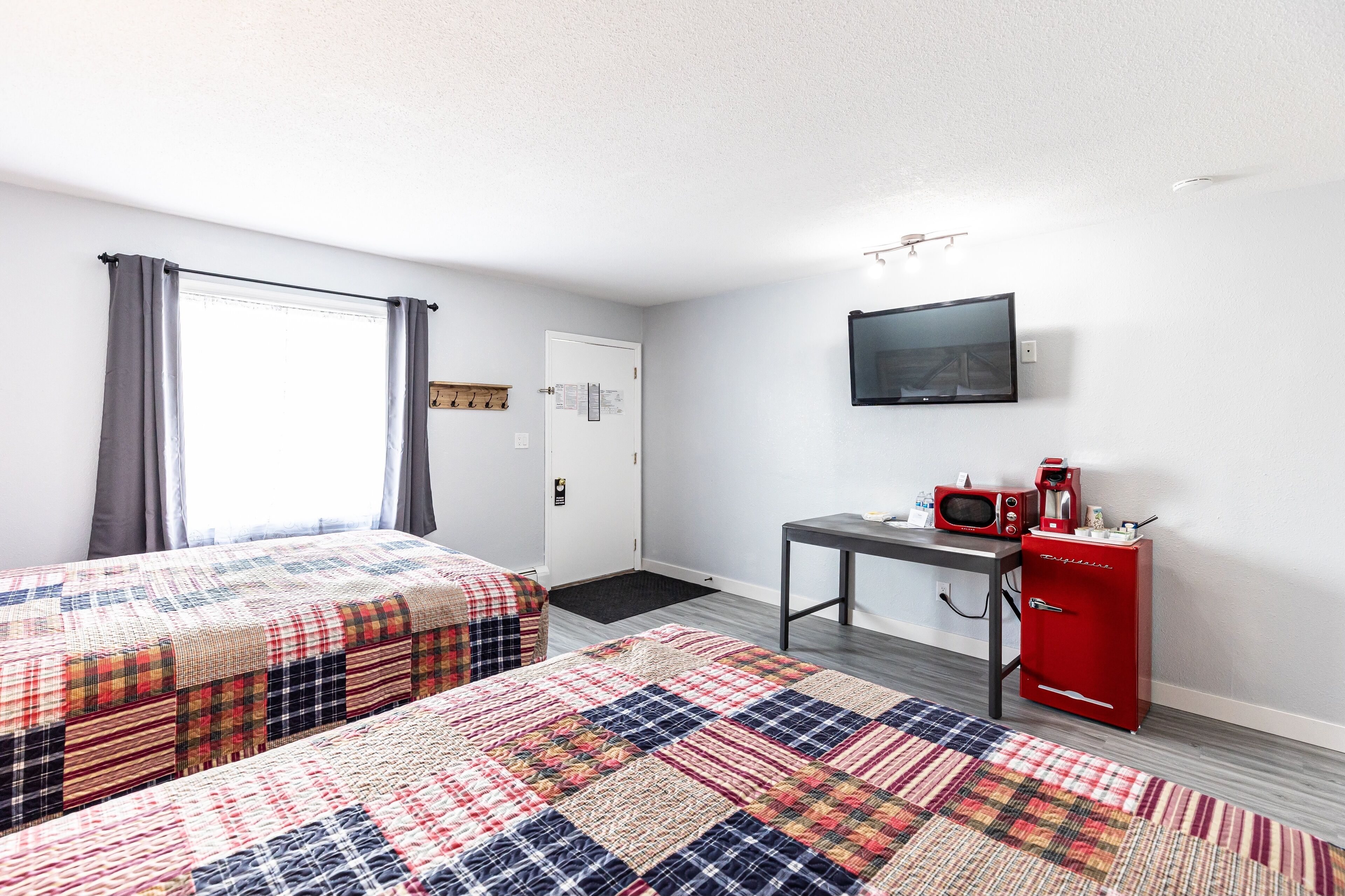 A room with two beds, a TV, a coffee maker, and a red cabinet.