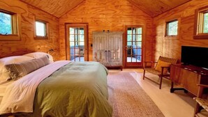A cozy wooden cabin bedroom with a bed, a desk, and a TV. - Modern Douglas Hideaway | Hot Tub & Patio (Douglas)