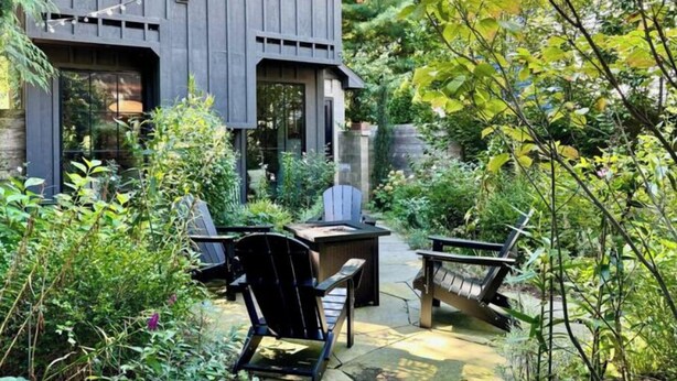 A modern house with a patio area featuring two Adirondack chairs and a small table. - Modern Douglas Hideaway | Hot Tub & Patio (Douglas)