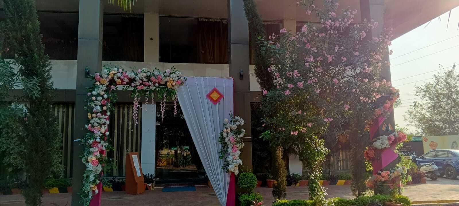 A building entrance decorated with floral arrangements and a draped fabric.
