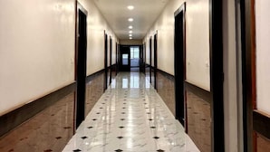 Un largo y estrecho pasillo con suelo de mármol e iluminación empotrada.