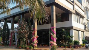 Un hotel moderno con estructura de dos pisos, amplias ventanas y un jardín bien cuidado con plantas y flores en macetas.