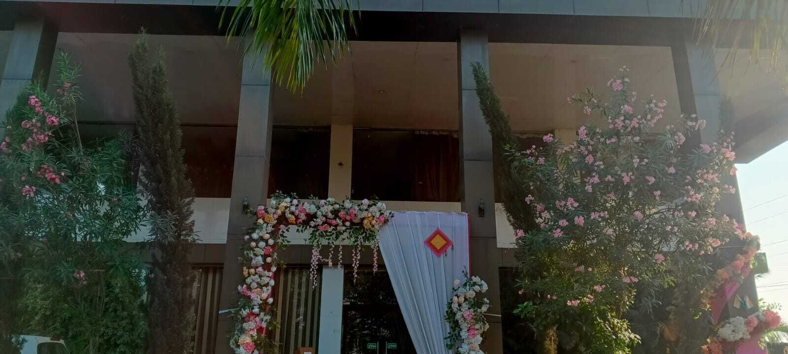 Fachada de edificio con un arco central adornado con flores y tela drapeada.