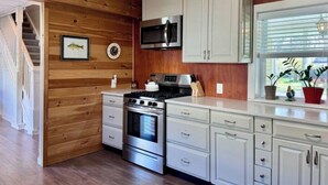 Eine moderne Küche mit Holzvertäfelung, Edelstahlgeräten und weißen Schränken.