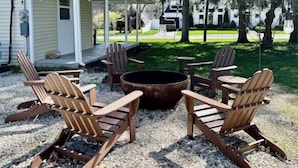 Eine Terrasse mit Adirondack-Stühlen und einem Feuerkorb.