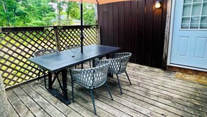 A wooden deck with a table and chairs, a large umbrella, and a wooden fence.