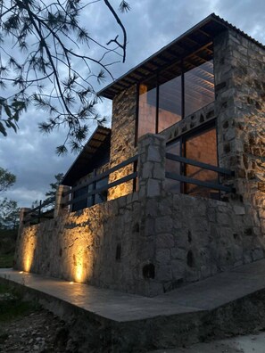 A stone building with large windows and a wooden deck.