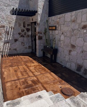 A stone-walled patio with a wooden floor, a bench, and a cactus planter.