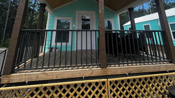 A small, single-story building with a wooden porch and a white door.