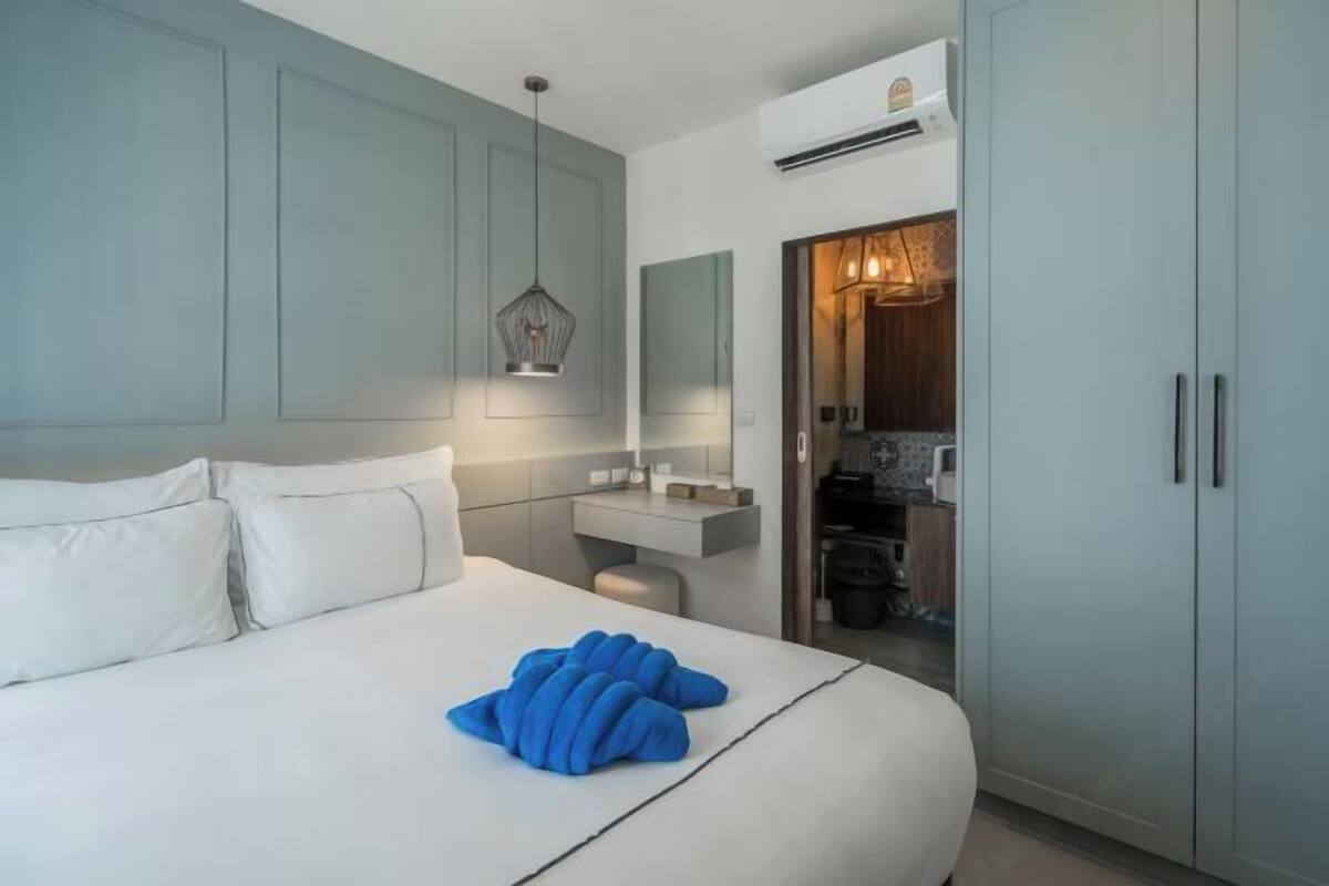 Een hotelkamer met een bed, nachtkastje, spiegel, kledingkast en een airconditioning.
