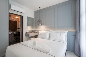 A hotel room with a large bed, a bedside table, a mirror, and a window with curtains. - Palmyrah Surin Beach Residence (Phuket)
